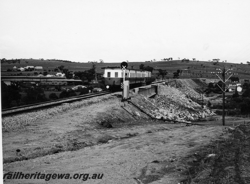 P17611
An unidentified ADF class Wildflower unit and 2 AYU class trailers on a special service to Albany travelling over the Avon River at West Northam. GSR line. This deviation was built as part of the standard gauge construction at Avon Yard. Note the rocks protecting the embankment and the former loco buildings to the left background.
