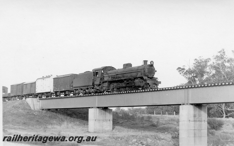 P17620
W class 958 steam locomotive hauling a goods train over the Preston River bridge enroute from Boyup Brook. PP line. Concrete abutment and pylons, steel girders visible.
