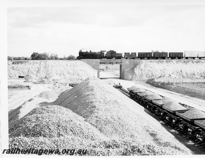 P17768
An unidentified PMR class locomotive on 37 Goods crossing the Kenwick Flyover. SWR line. Note the loaded LA ballast hoppers in the foreground and the ballast stockpile.
