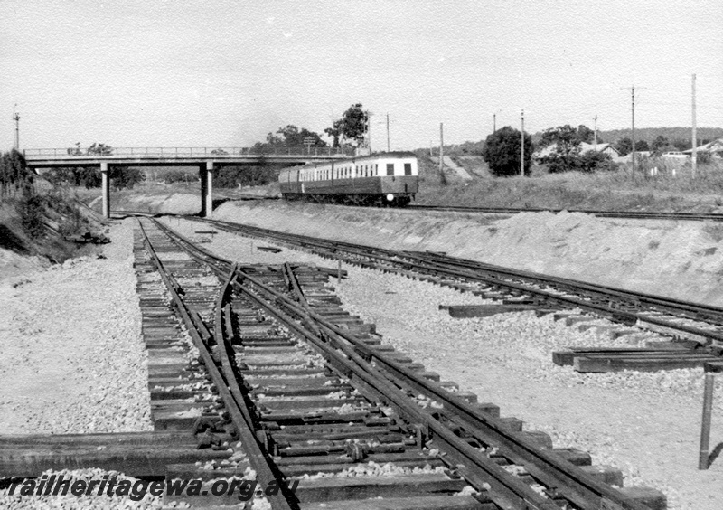 P17805
Perth to Chidlow 'Wildflower' set enroute to Chidlow Great Eastern Highway at Bellevue. Unidentified power car and trailers. Rear view of train and note dual gauge trackwork in foreground. ER line.
