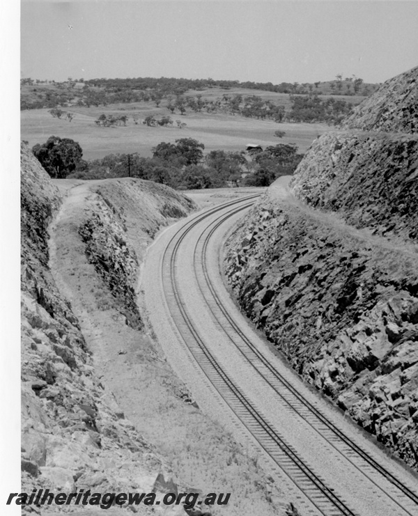 P17860
Windmill Hill cutting east of Toodyay as seen from the top of the cutting looking in an easterly direction. Note the bank shaping process utilised. The portion of the cutting to the right is 100' high.
