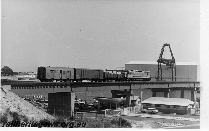 P17893
L class 257, on No 1208 goods train comprising GX class 5244 (NSWGR), VD class 1371 (Commonwealth Railways (CR)), WBC class 867 (WAGR), crossing steel and concrete bridge, Fremantle, Swan River, wharves, warehouse, ER line
