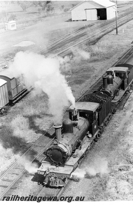 P18207
2 of 3, G class 118 and G class 67 steam locomotives, elevated front view, passing through the station yard, heading north, goods shed, Pinjarra, SWR line.
