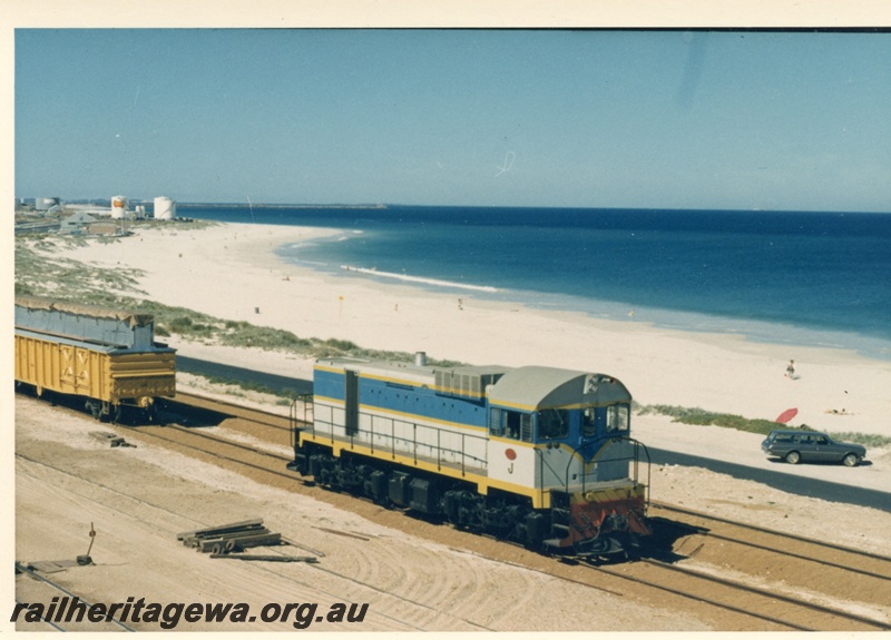 P18299
J class diesel loco, manual point lever, beach, road, storage tanks in background, Leighton yard, side and end view, c1966
