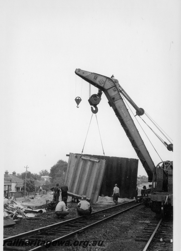 P18324
Cowans Sheldon crane, lifting operations, workers, houses, road, demolition of West Midland station, ER line, view from track level 
