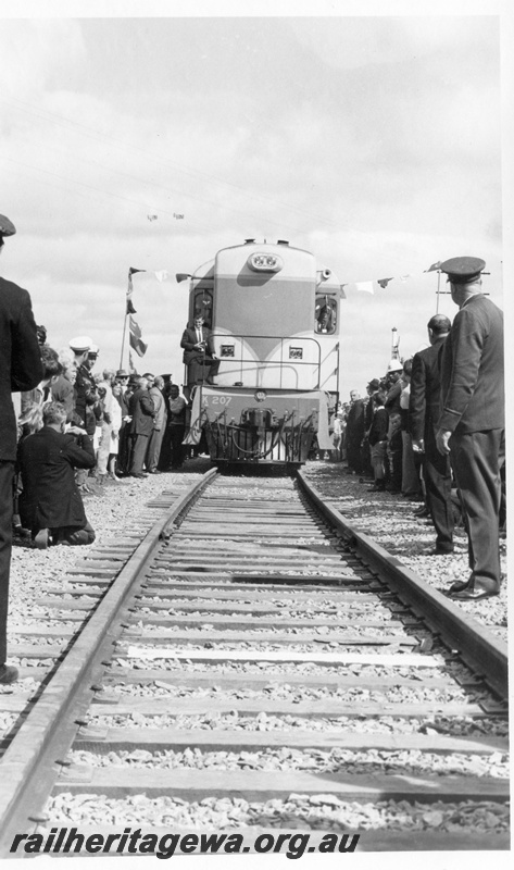 P18471
2 of 12 images relating to the ceremony for the linking of the standard gauge railways at Kalgoorlie, K class 207, driven by WA Premier Brand over the recently completed section of standard gauge track, spectators, Kalgoorlie, front on view
