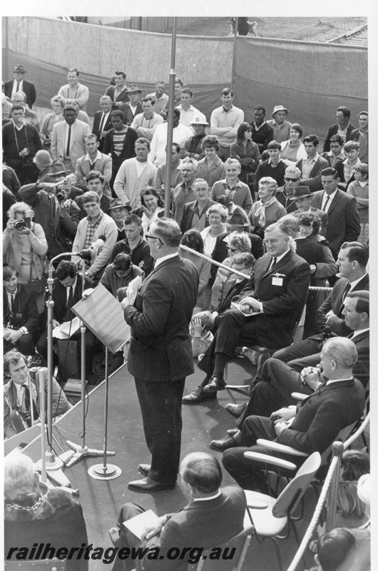 P18476
7 of 12 images relating to the ceremony for the linking of the standard gauge railways at Kalgoorlie, WA Premier Brand on the dais addressing the audience, seated on the dais from left to right are Kalgoorlie Mayor Alman, Commonwealth Railways (CR) Commissioner Smith, WAGR Deputy Commissioner Pascoe, Federal Minister of Transport Sinclair, WA Minister of Transport O'Connor, and WA Minister of Industrial Development Court 
