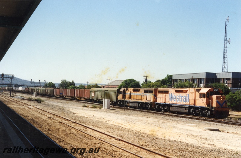 P18639
 L class 263 diesel locomotive and a sister unit hauling SCT's Dynon to Forrestfield freight train passing the Midland Signalling Control Centre. Both locomotives painted in two different orange Westrail colour schemes. The trackage in the foreground is narrow gauge for tourist trains to access Midland Terminal.
