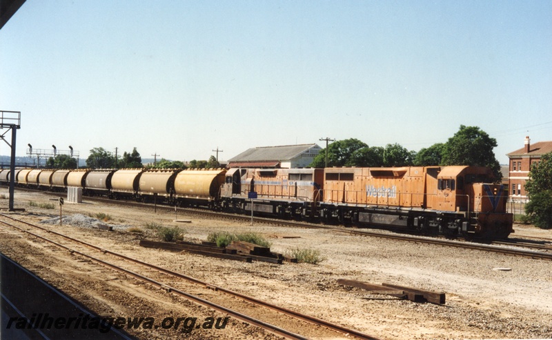 P18640
Two L class diesel locomotives heading a loaded grain train consisting of a mix of WW and WWA class grain hopper wagons. The train is enroute to Kwinana and is passing the former Midland Workshops. Both locomotives painted in different Westrail orange colour schemes.
