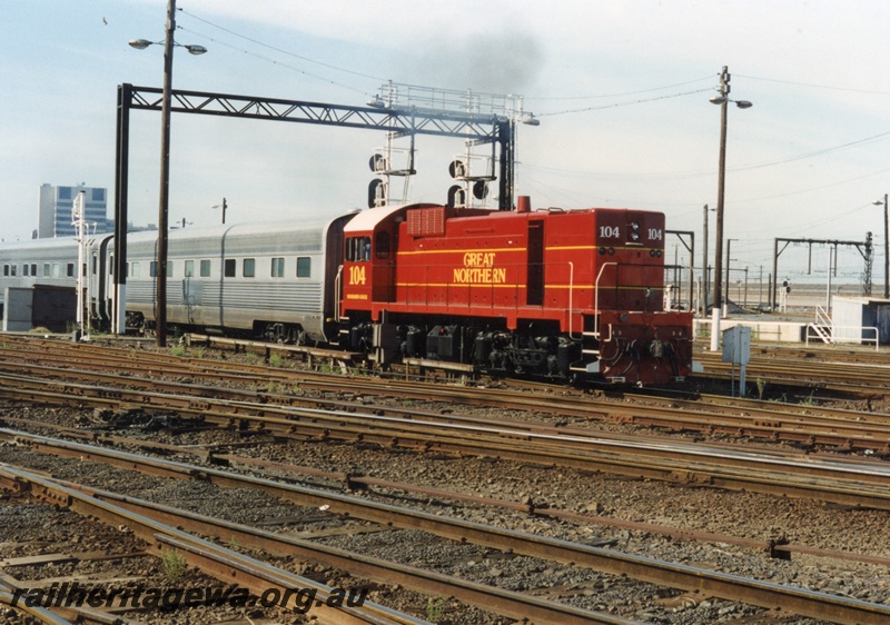 P18642
I of 6 views of J class 104 diesel locomotive shunting 'Overland' passenger stock at Spencer Street Melbourne. The locomotive was formerly a Westrail unit and here it is painted in Great Northern colour scheme of maroon. 
