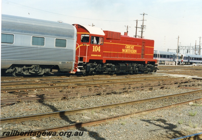 P18644
3 of 6 views of J class 104 diesel locomotive with a standard gauge carriage at Spencer Street Yard Melbourne. Victorian Railways Sprinter railcars to right front of the J class. 
