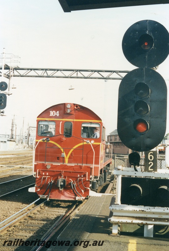 P18647
J class 104 diesel locomotive, in Great Northern Railways colour scheme entering the carriage cleaning sheds at Spencer Street Melbourne. Dual gauge (broad & standard) trackage in front of the locomotive. The type of signals utilised by Victorian Railways is also evident.
