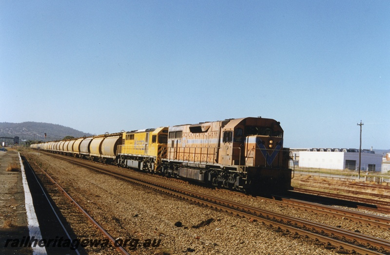 P18652
L class 273 and Q class 314 standard gauge diesel locomotives heading a loaded standard gauge grain train through Midland enroute to Kwinana. The building to the right of the locomotives was the former temporary Station structure erected at East Perth prior to the construction of the Westrail Centre.
