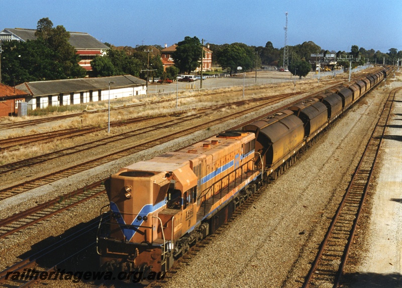 P18653
D Class 1561 heading a Down train with mineral sands XY Class hoppers backloaded with coal to Chandala passing through Midland. The white building to the left is the former workshop workers bicycle shed.
