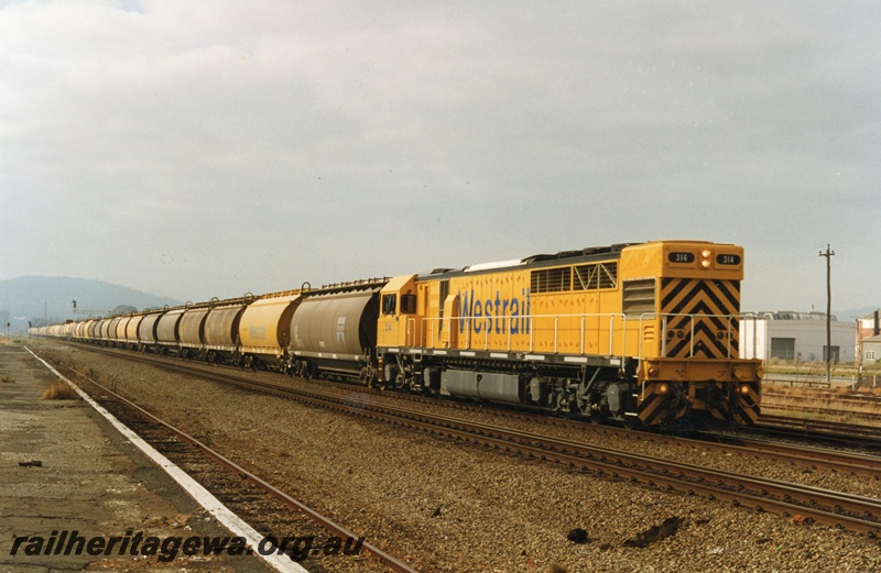 P18654
Q class 314 standard gauge diesel locomotive, travelling long hood forward, is hauling a loaded grain train through Midland. Locomotive painted in Westrail yellow and is one of 19 in service, ER line.
