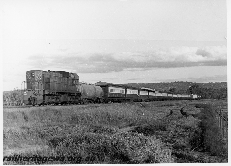 P18711
AA class 1515, in green livery with red stripe, on passenger train, with tanker wagon, rural setting, front and side view
