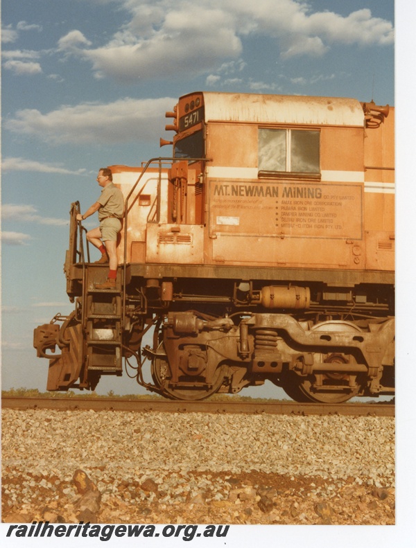 P18754
Mount Newman (MNM) M636 class 5471 side view of cab, with co driver on steps of locomotive at Walla siding. 
