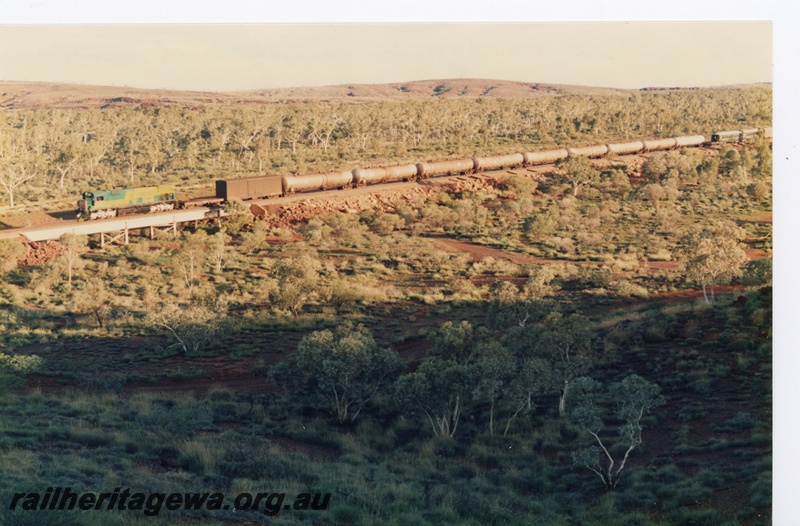 P18787
Mount Newman (MNM) M636 class 5488 (in bicentennial livery) hauling supply train with sundowner coach near Newman..
