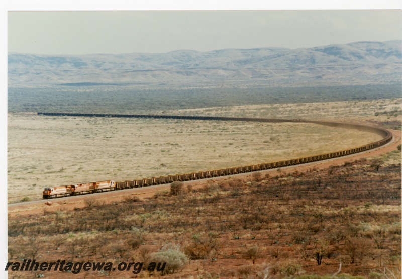 P18792
Mount Newman (MNM) M 636 class 5495, 5467, 5477 haul loaded ore train near Garden. View of whole train.
