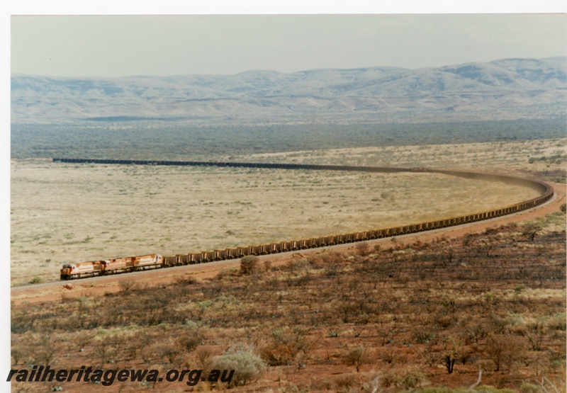 P18792
Mount Newman (MNM) M 636 class 5495, 5467, 5477 haul loaded ore train near Garden. View of whole train.
