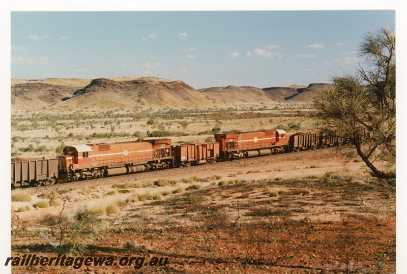 P18794
Mount Newman (MNM) M636 class 5470, 5469 Locotrol units in centre of train near Garden. Mesa's in background.
