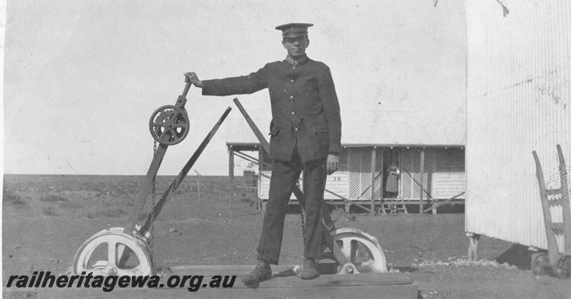 P19020
Point levers, station building, hand trolley, Thomas French in uniform, tent home number 36, woman in doorway, TAR line 
