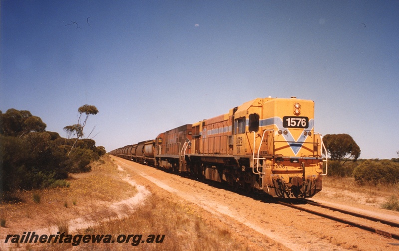 P19125
DA class 1576 and unidentified P class haul loaded grain train towards Mollerin. Both locomotives painted in Westrail orange. KBR line.
