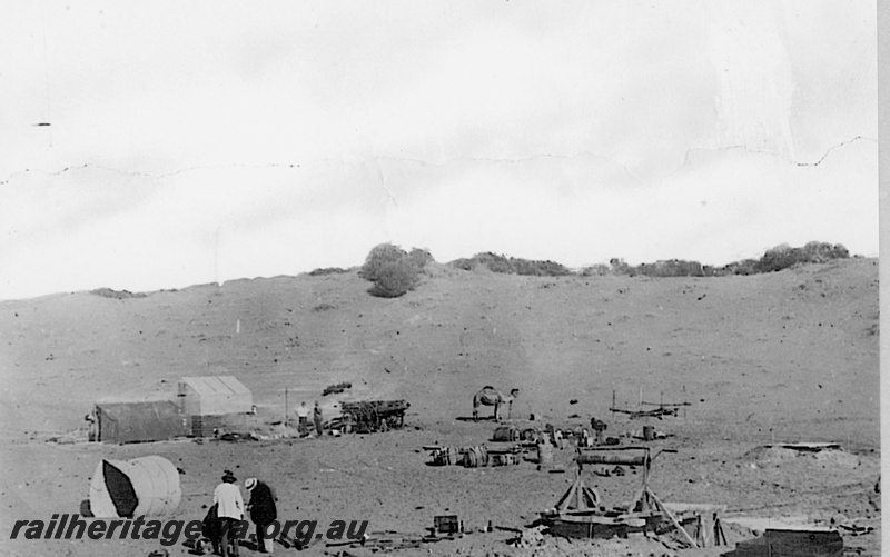 P19187
Commonwealth Railways (CR) camp, tents, wagon, well, workers, camel, TAR line
