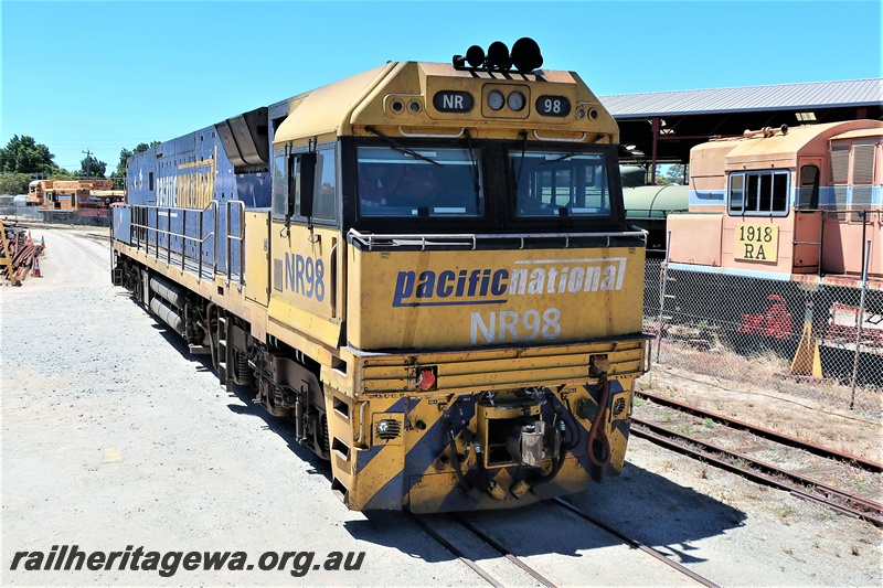 P19560
Pacific National NR class 98 in the blue and yellow livery passing through he site of the Rail Transport Museum, Bassendean, side and front view
