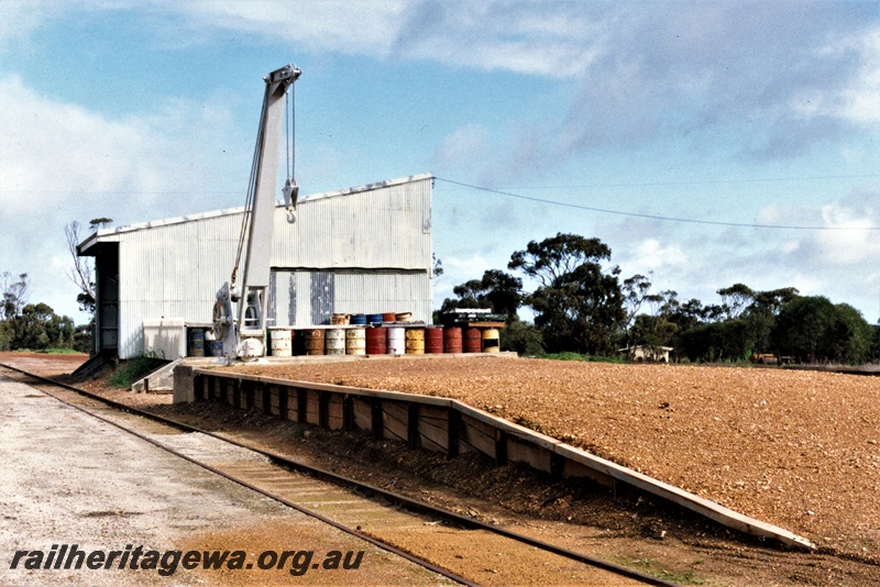 P19589
Platform crane, goods shed, loading platform, Goomalling, EM line, side and rear view of the shed, note the 44 gallon drums at the side of the shed.
