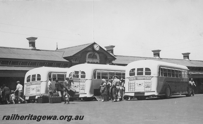 P19645
Railway Road Service buses parked in the forecourt of the Bunbury Station, passengers around the buses, end and side view
