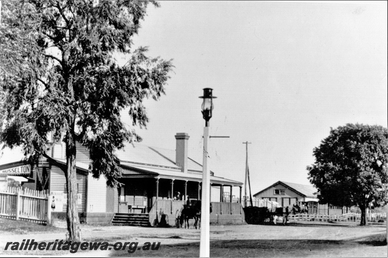 P19702
Station building, street gas lamp, Busselton, streetside view, C1900. The station name can be seen on the end of the station platform canopy.
