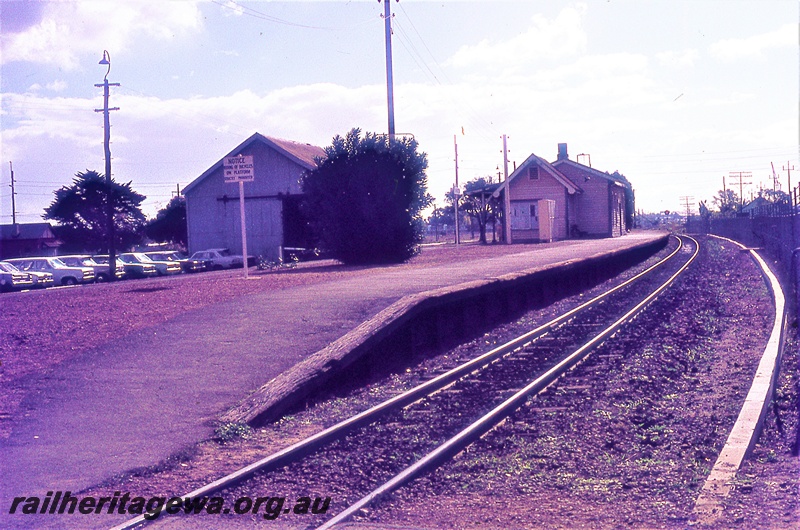 P19725
Platform, station building, notice prohibiting bicycling, tracks, goods shed, carpark, Cannington, SWR line, track level view
