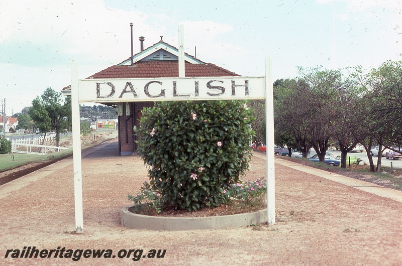 P19849
Station nameboard, platform, station building, circular garden bed and shrub on platform, Daglish, ER line, view from platform
