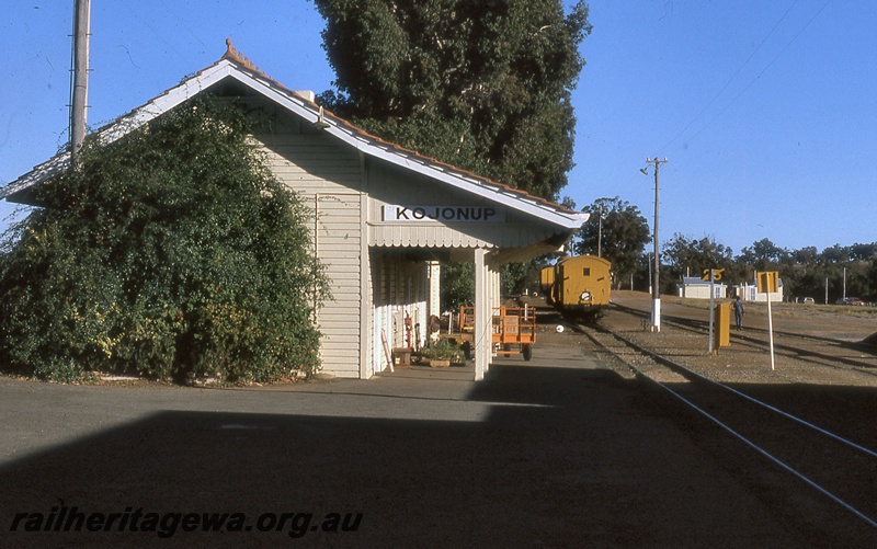 P19934
Station building, station nameboard, platform, vans, luggage cart, tracks, Kojonup, DK line
