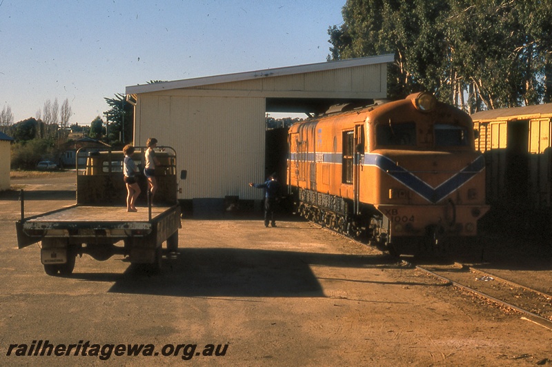 P19935
XB class 1004, moving through goods shed class 3, van, truck, onlookers, railway employee directing movement, Kojonup, DK line
