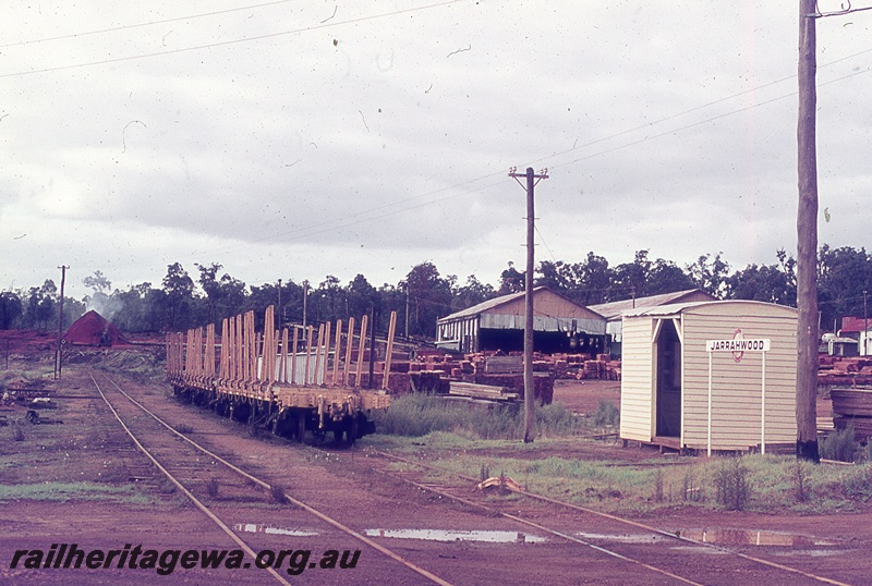 P19949
Rake of flat wagons with bolsters, station shed, station nameboard, tracks, timber piles, sheds, Jarrahwood, WN line
