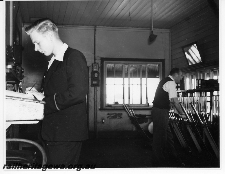 P20008
Interior of signal box, one signalman writing notes, another signalman pulling lever, East Perth, ER line
