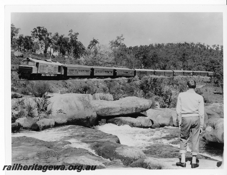 P20019
X class diesel on passenger train, with waterbags hanging from some carriages, rapids and sightseer in foreground, National Park, ER line
