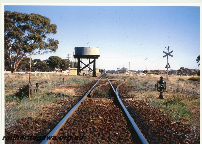 P20030
Station and trackside buildings, track, points, siding, water tower with a Squatters tank, , level crossing, Yellowdine, EGR line, track level view looking west
