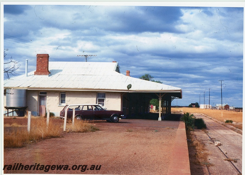 P20034
Disused station building, platform, water tank, maroon Holden station sedan on platform, overgrown track with rock on it, view along platform, Yalgoo, NR line, same as T05155
