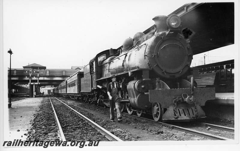 P20105
PR class loco on passenger train, overhead road bridge, bracket signals, driver walking beside loco wearing black shirt and white tie, platform, bench seat, canopy, Perth city station
