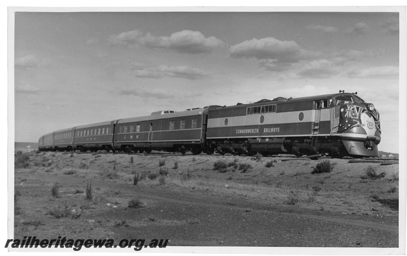 P20123
Commonwealth Railways (CR) GM class diesel, with nose festooned with national flags, on the new Trans-Australian train consisting of Wegmann carriages, inaugural run, TAR line, side and front view
