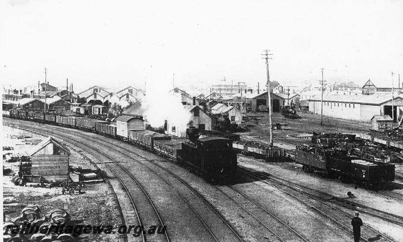 P20251
Fremantle - view of railway yards and K class hauling goods train. FA class louvered van in train consist. ER line.
