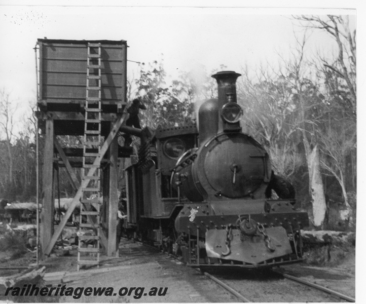 P20260
Millars G class locomotive taking water in bush setting. The locomotive is hauling a train of logs.
