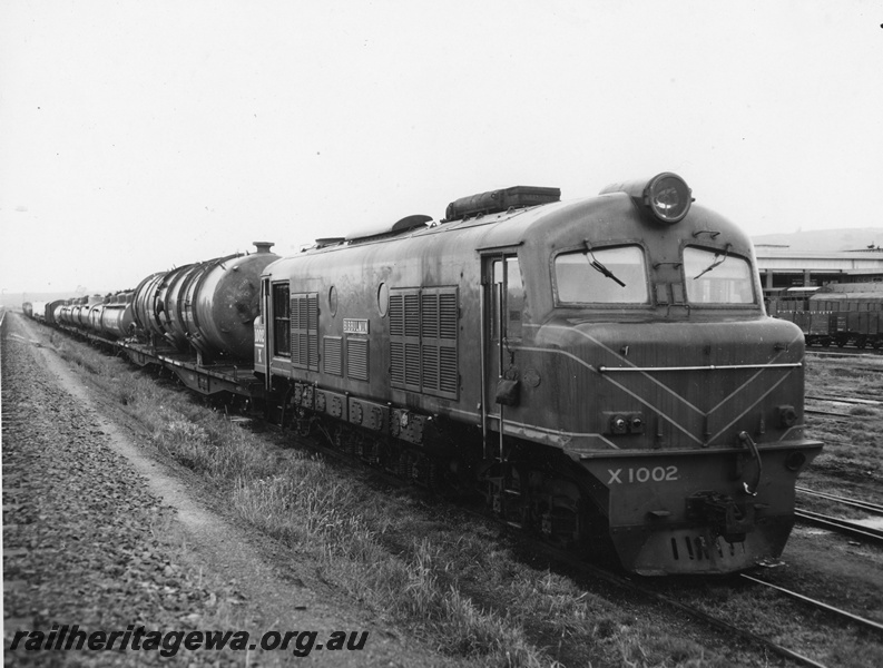 P20269
X class 1002 on goods train including at the front two QU class wagons, laden with a large 70 t 64 ft Bernard Smith Sydney pressure vessel, in transit from Cooks River to Kwinana, front and side view
