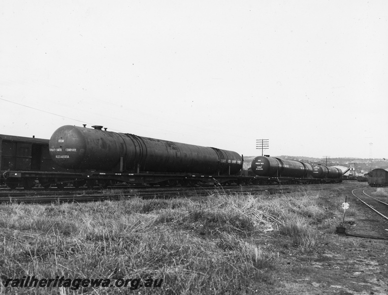 P20271
Rake of QU class wagons including QU class wagon 25023, loaded with large Bernard Smith pressure vessels, vans, sidings, point lever, Midlands, ER line, end and side view  
