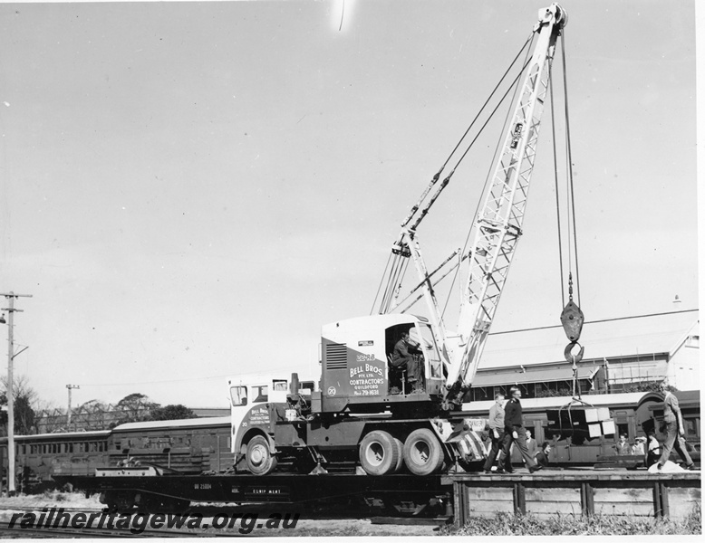 P20276
Goods despatch to the South West flood zone, No 1 of 3, QU class wagon 25004, at dock platform, with Bell Bros mobile crane 22 R B on board, during loading operations, workers, Midland, ER line, side view
