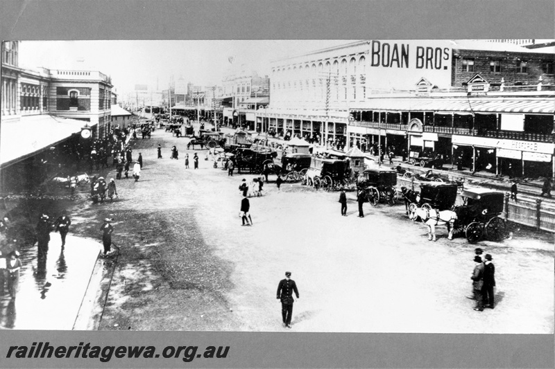 P20335
View of the front of Perth station, buildings, station clock, pedestrians, horse drawn carriages, Boan Bros store, view from elevated position looking east
