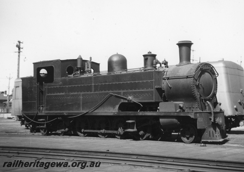 P20366
K class 102 in use for steam cleaning of other locomotives, at East Perth loco shed. ADT trailer behind K class. ER line.
